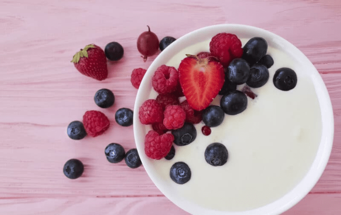 A bowl of Greek yogurt topped with raspberries, blueberries, and strawberries.