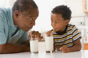 Old man drinking milk with his grandson