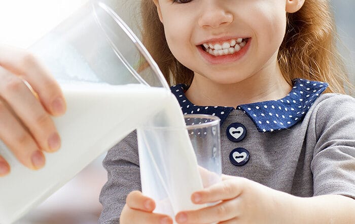 little girl drinking milk that will help keep her teeth healthy