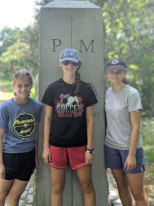 Three young girls standing near a monument.