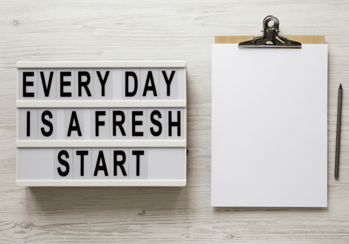 A sign with the phrase "Every day is a fresh start" next to a clipboard and a pencil.