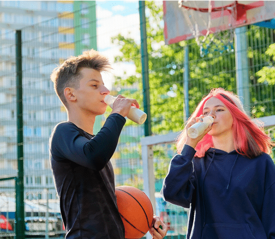 young adults drinking milk on a basketball court