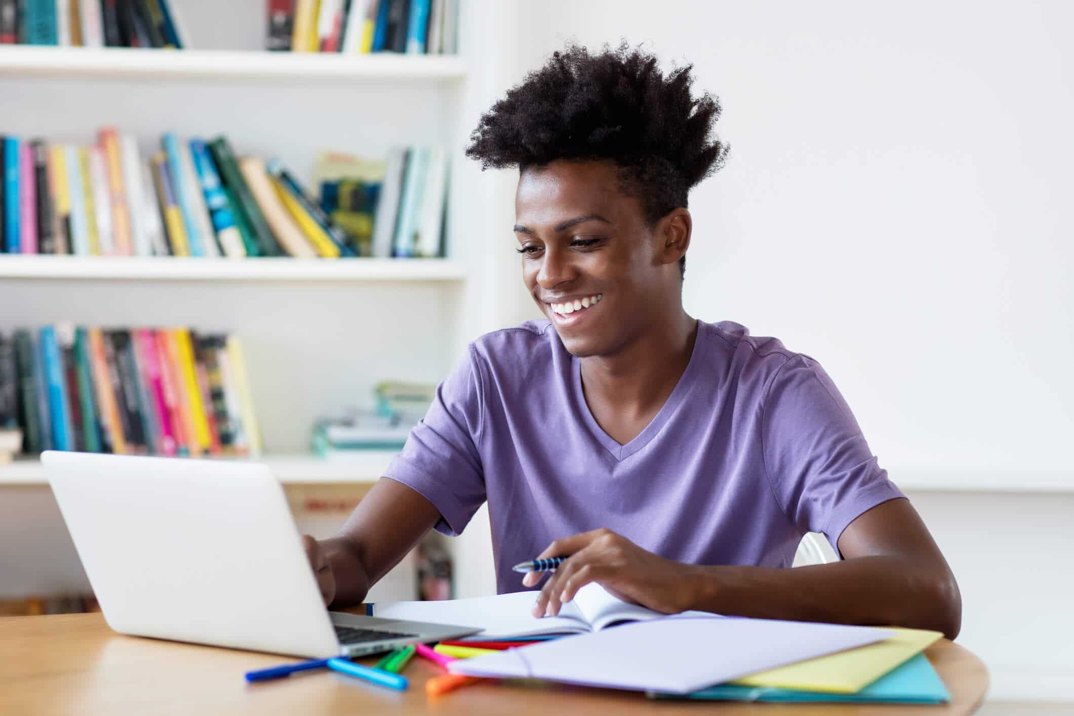 Young man smiling while doing homework