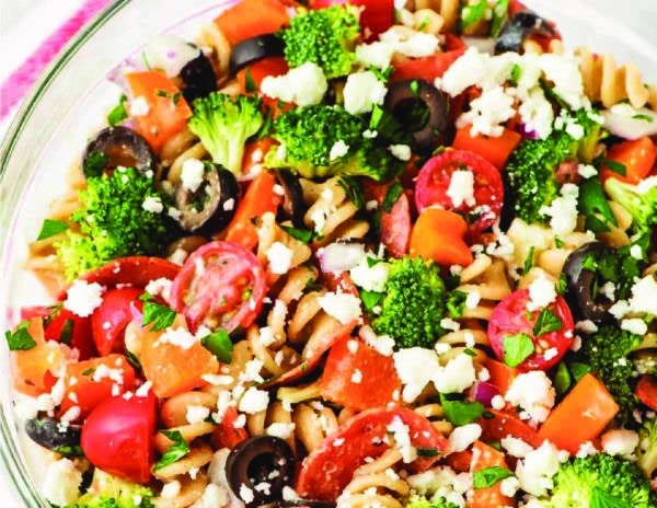 A pasta salad served in a bowl with vegetables.