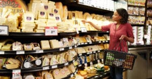A woman selecting cheese at the store.