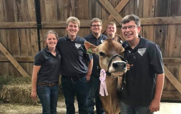 Young people smiling next to a calf