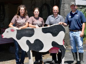 People standing behind a wooden cow