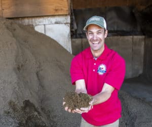 Man smiling and holding dirt in his hands