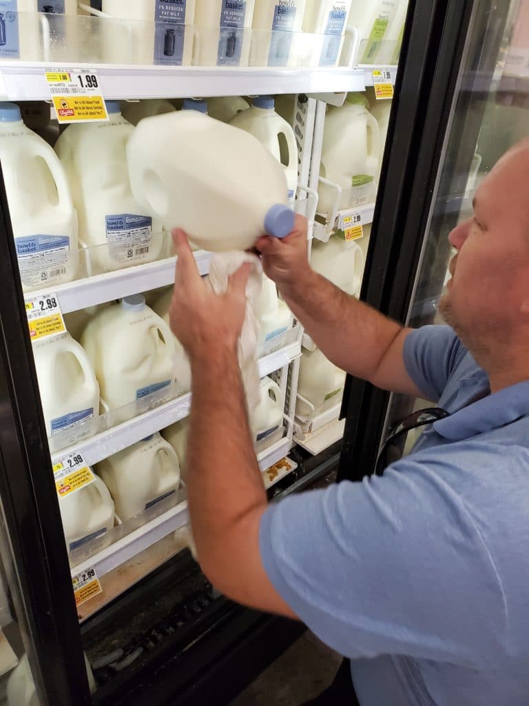 Man restocking milk at a grocery store