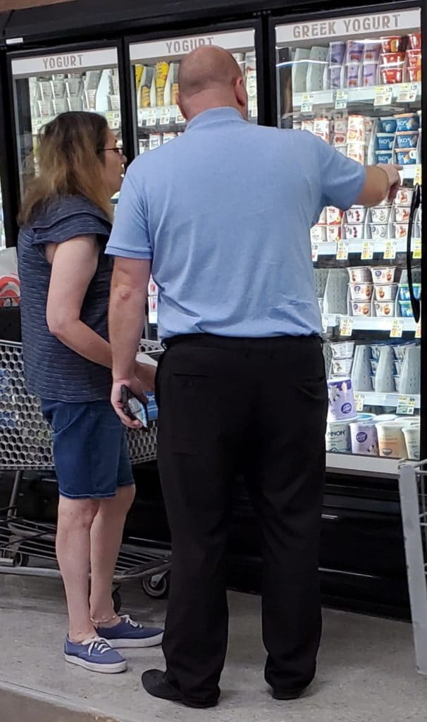 Man showing woman yogurt in the dairy aisle