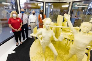 People posing beside a butter sculpture