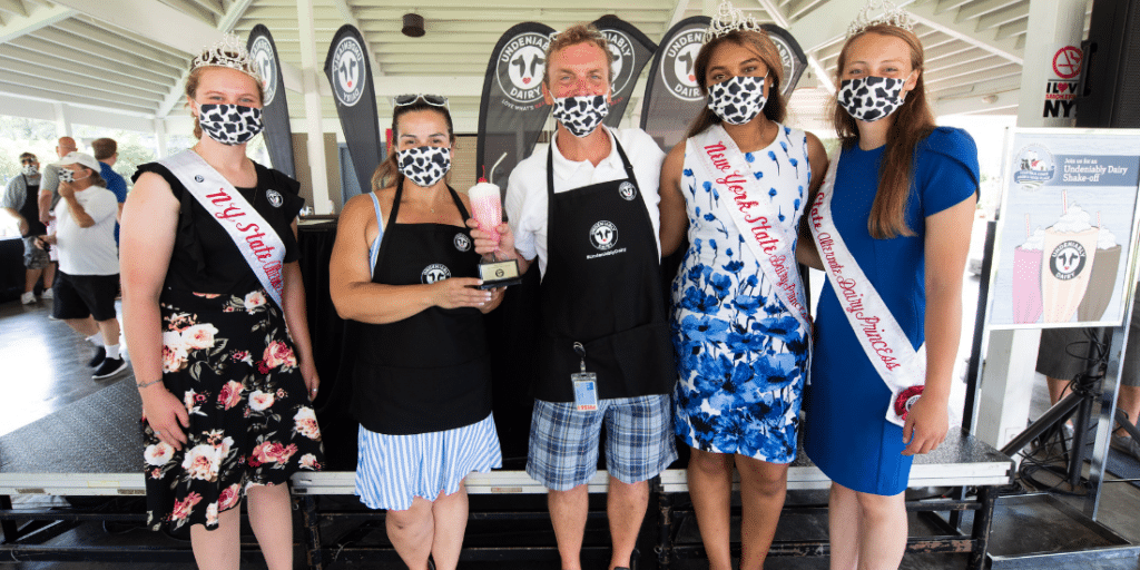 People at a dairy festival posing for a picture while one holds an award.