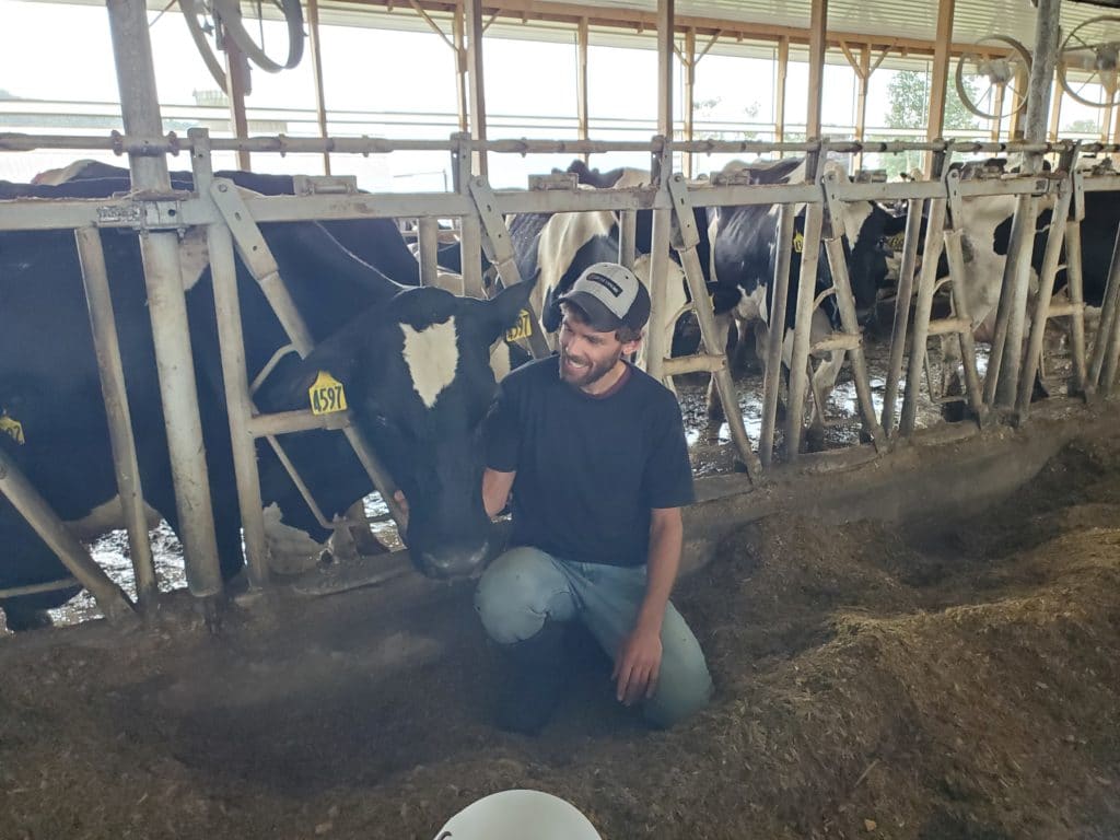 farmer with a cow peeking over his shoulder