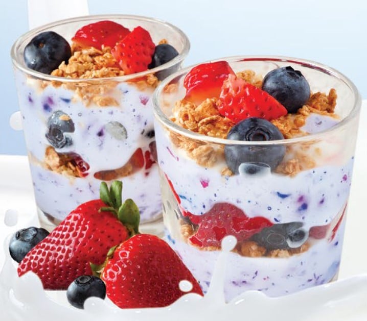 Two glasses of yogurt parfait with blueberries, strawberries, and granola.