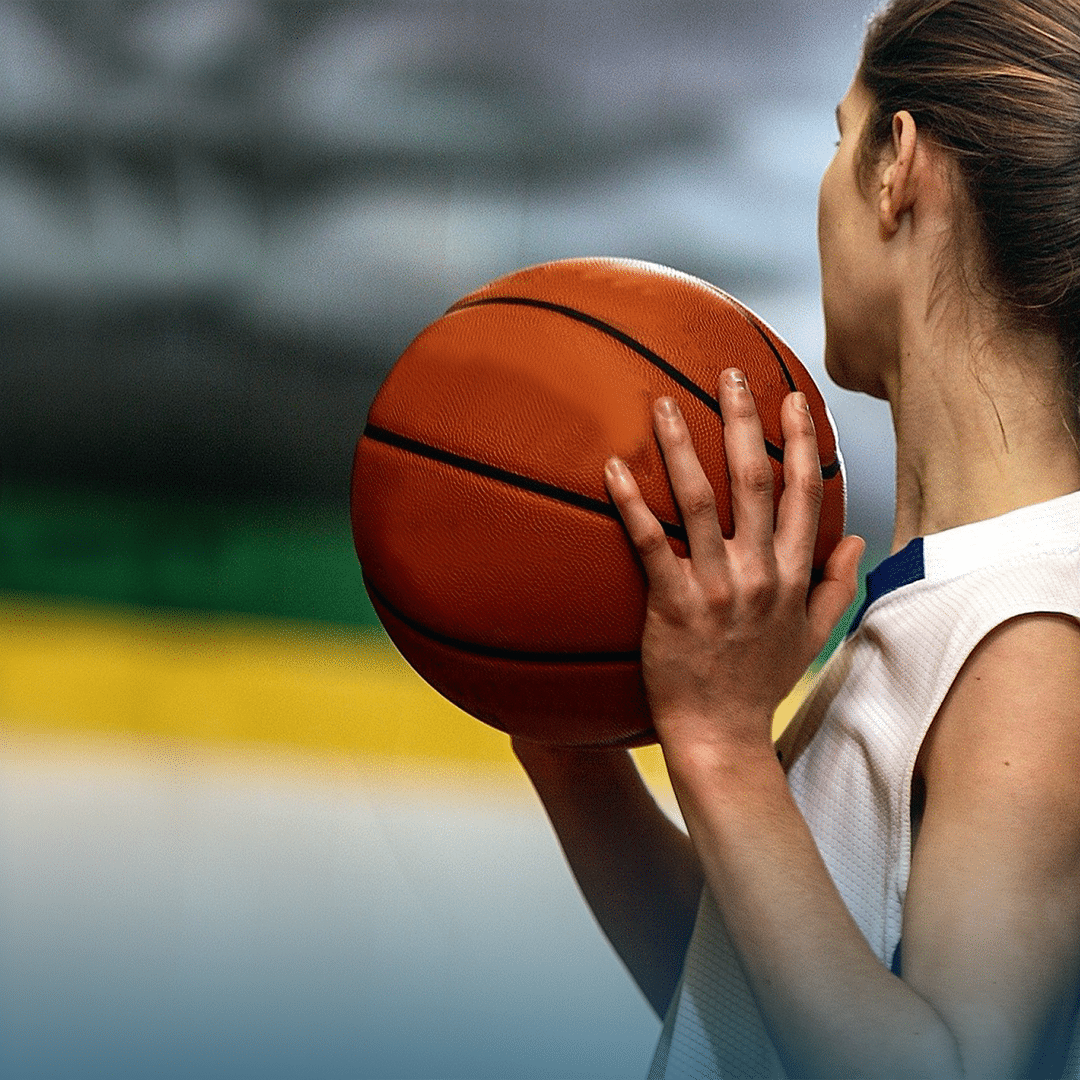 girl holding a basketball and looking into the distance away from the camera