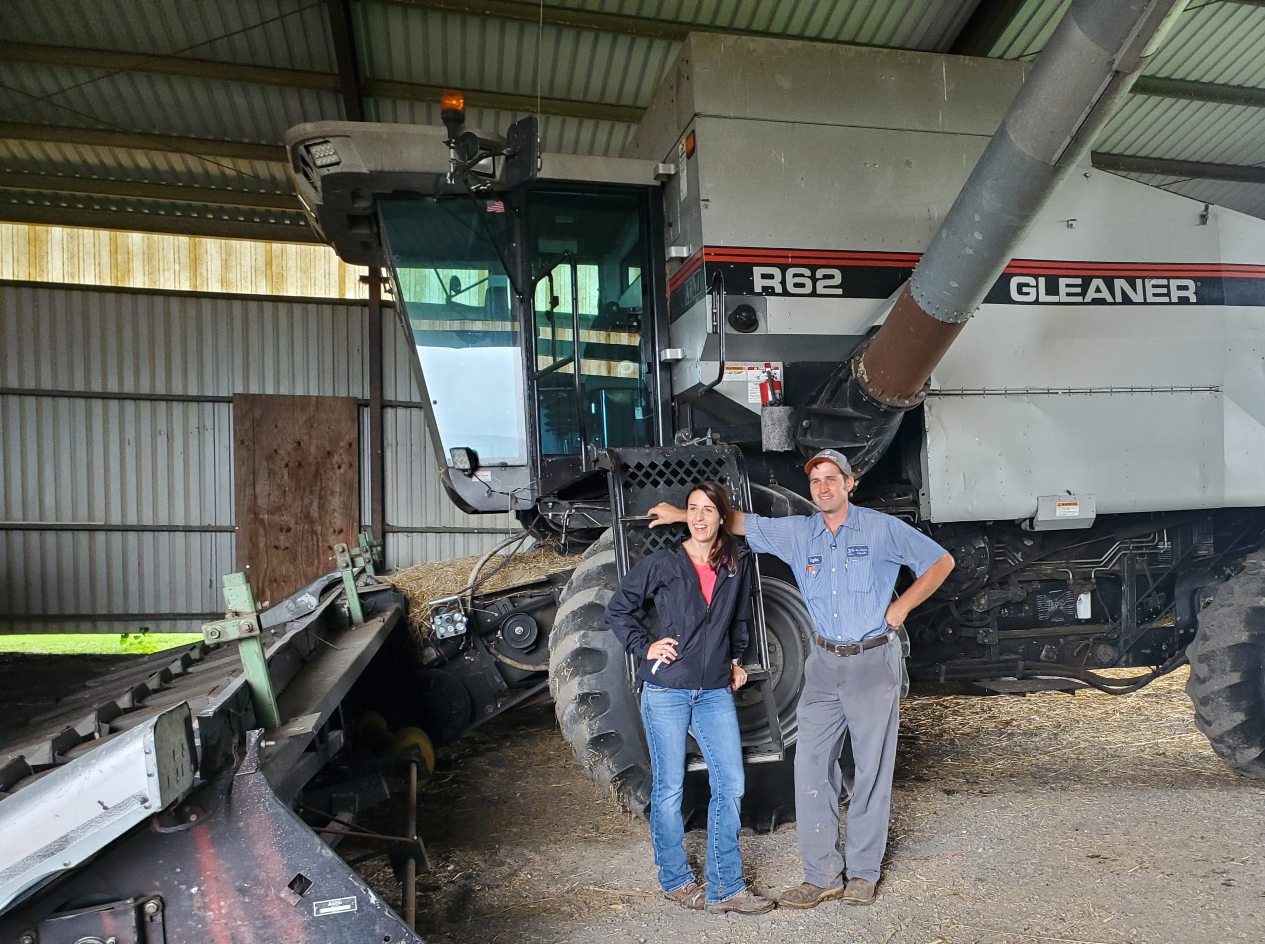 two people by a large piece of farm equipment
