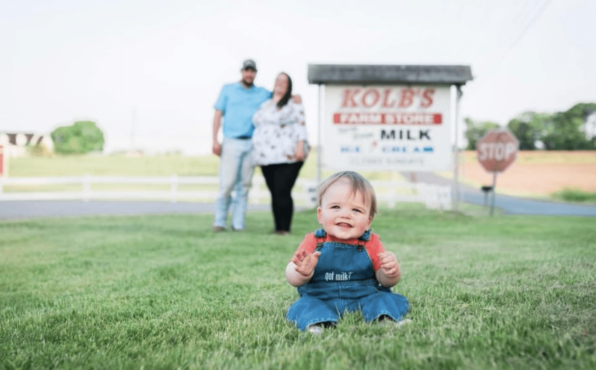 A cute baby in dungarees with the phrase "Got milk?" sitting on a green grass.