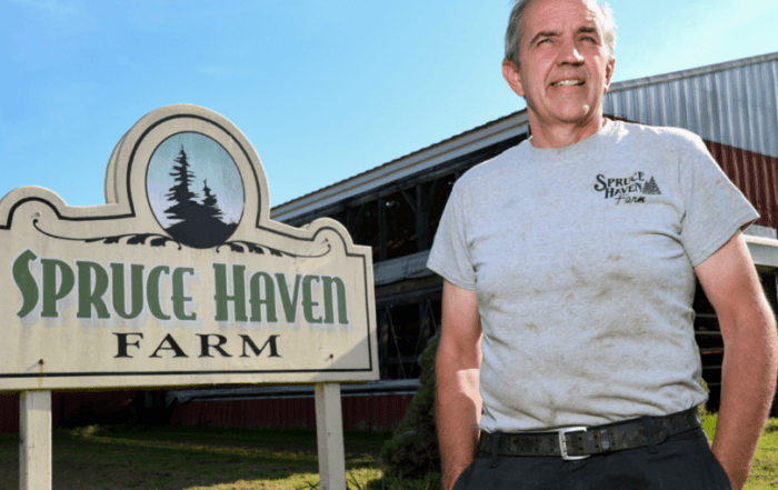 Man standing next to a Spruce Haven Farm sign