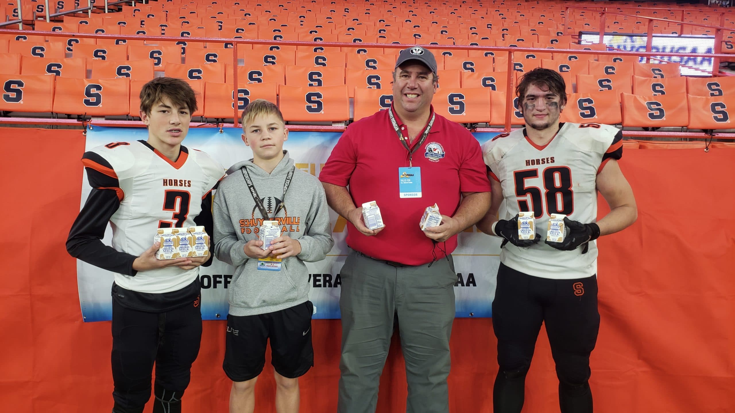 Football coach and his players holding milk
