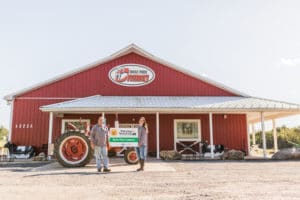 Winning farmers holding a sign outside of their barn