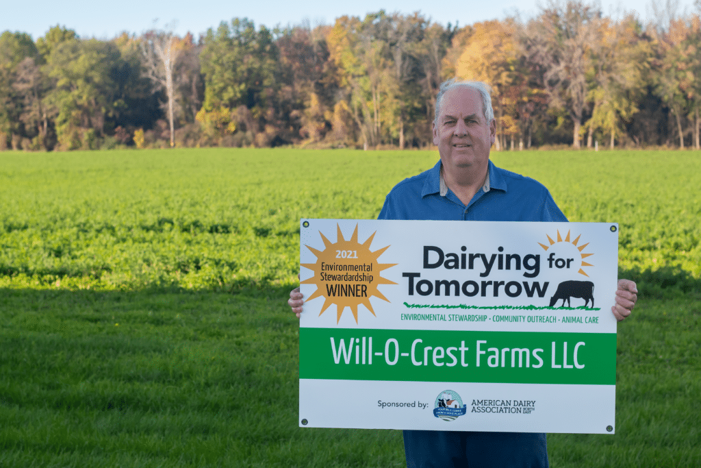 Winning farmer holding a sign in front of a pasture