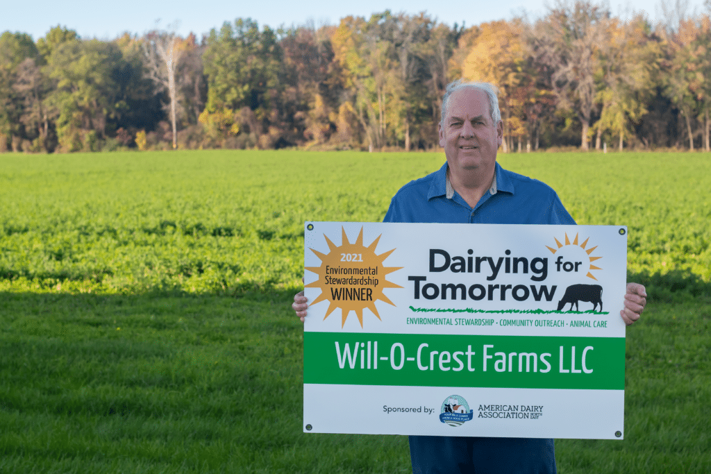 7. 2021 DFT signs. Will-O-Crest.Bill Young Winning farmer holding a sign in front of a pasture