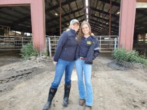 Two girls pose outside of a barn