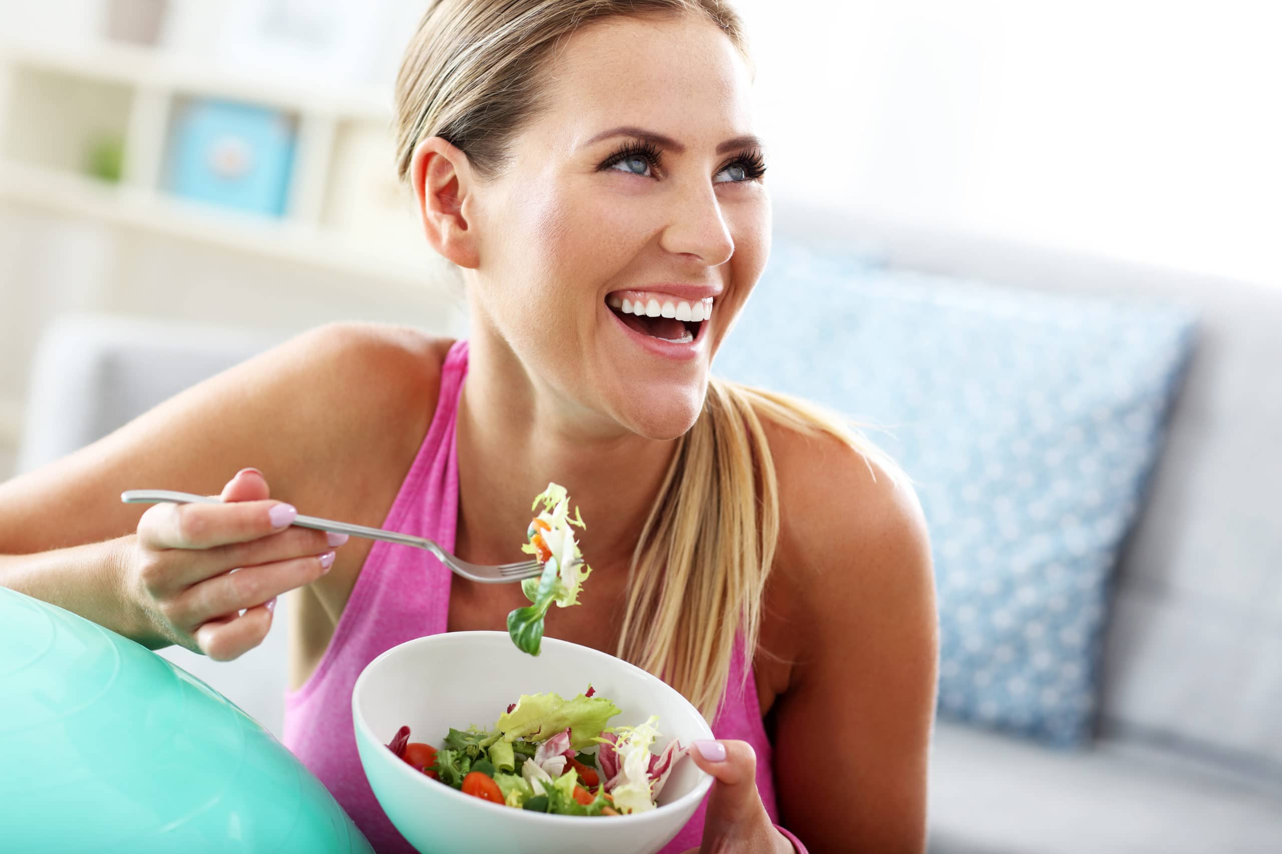 Woman laughing while eating a salad