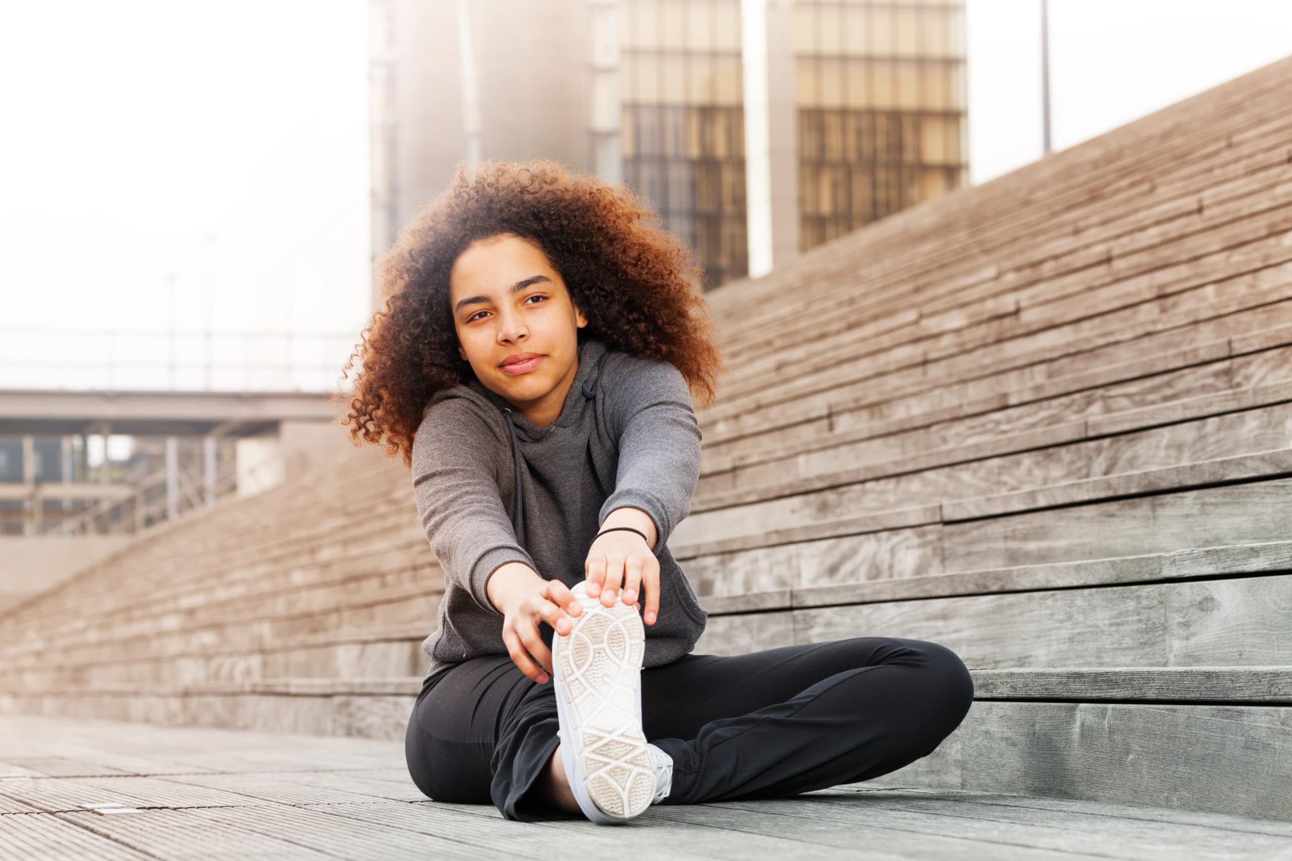 Young woman sitting down and stretching her legs
