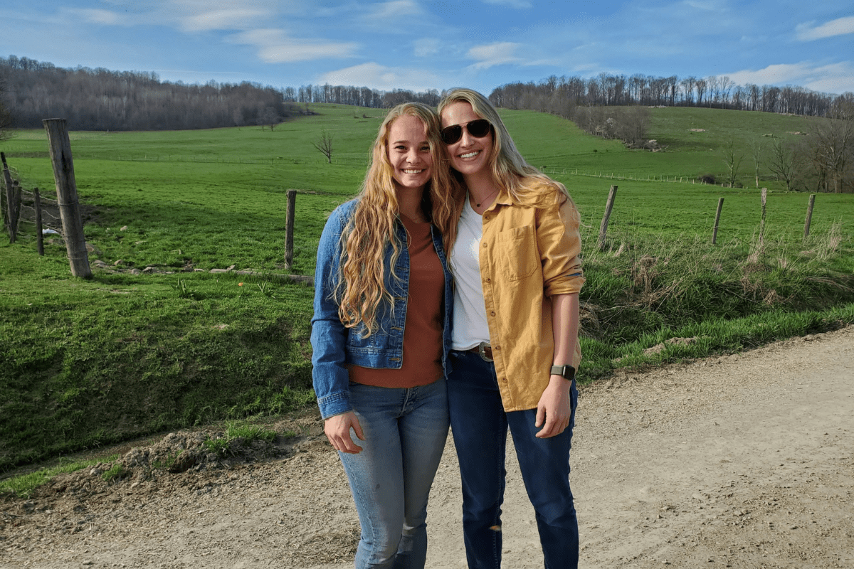 Stephanie and Hayley Painter, dairy farmers, are captured posing on their farm.