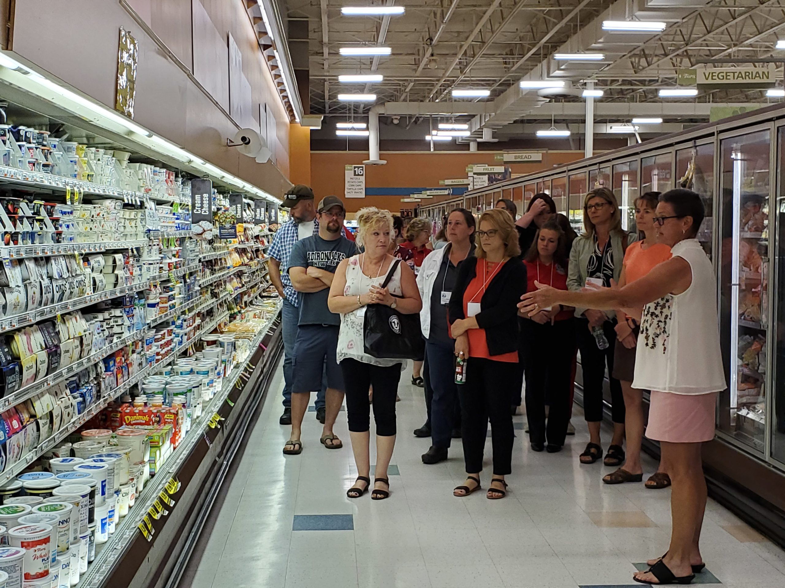 A group of people standing in front of a dairy counter in a supermarket.