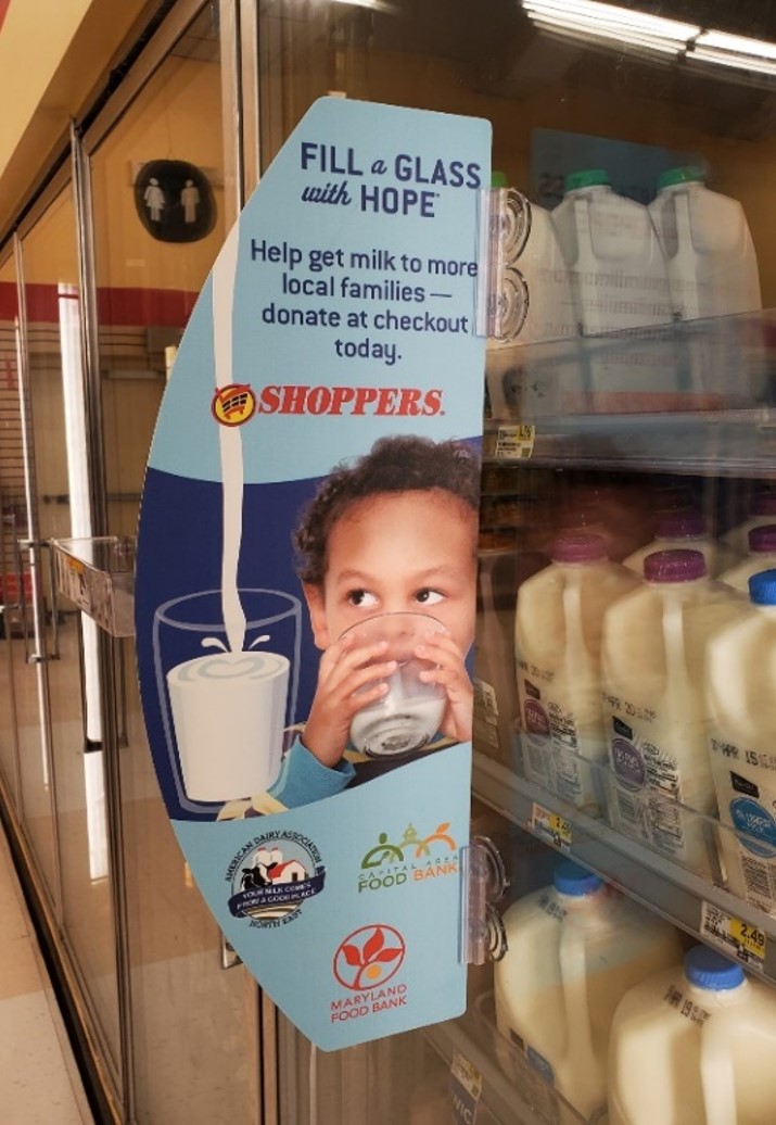 Inside a grocery store, a milk refrigerator with an advertisement "Fill a Glass with Hope.