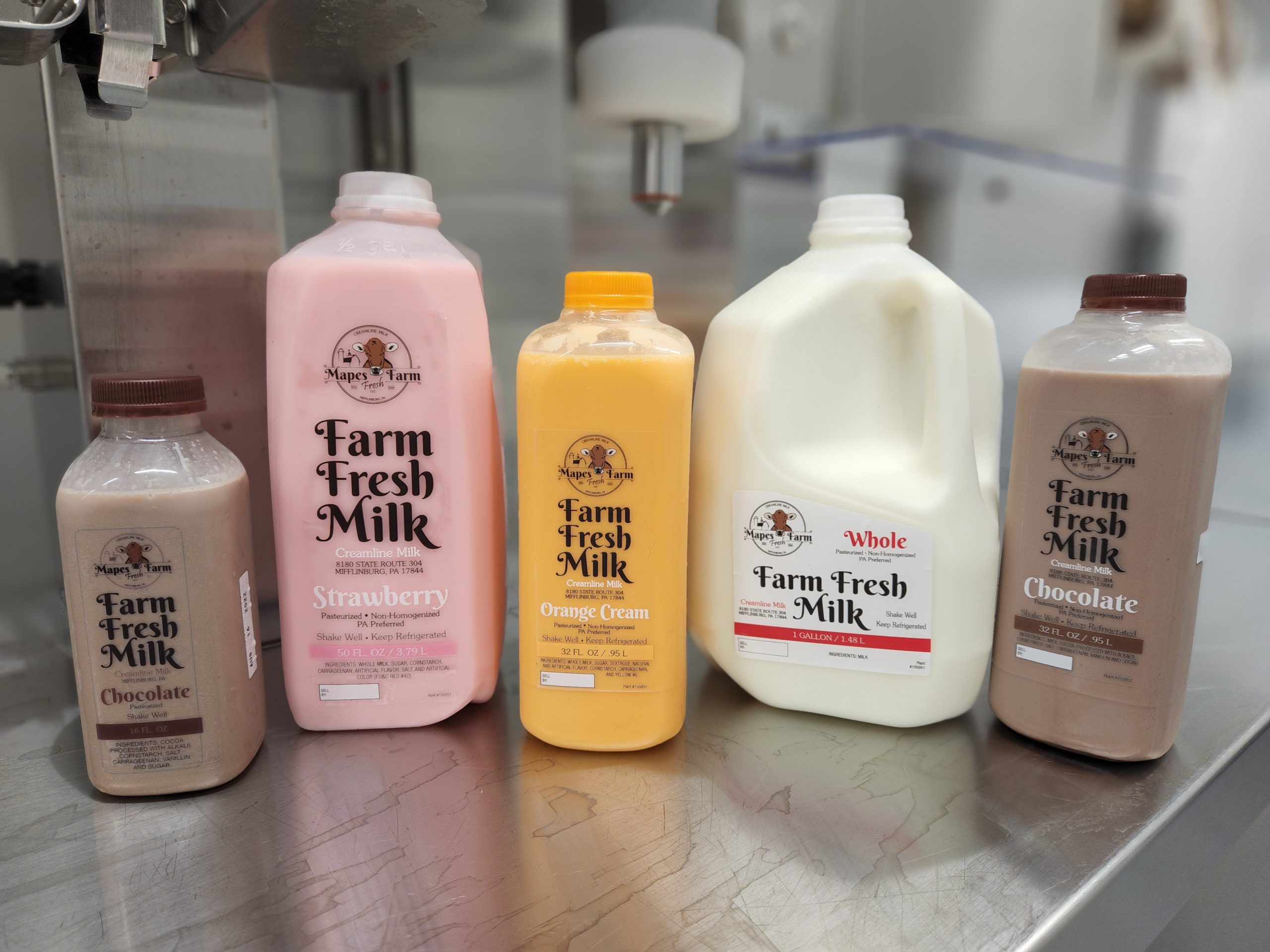 Two bottles of chocolate milk, a bottle of strawberry milk, a bottle of orange cream, and a bottle of whole milk.