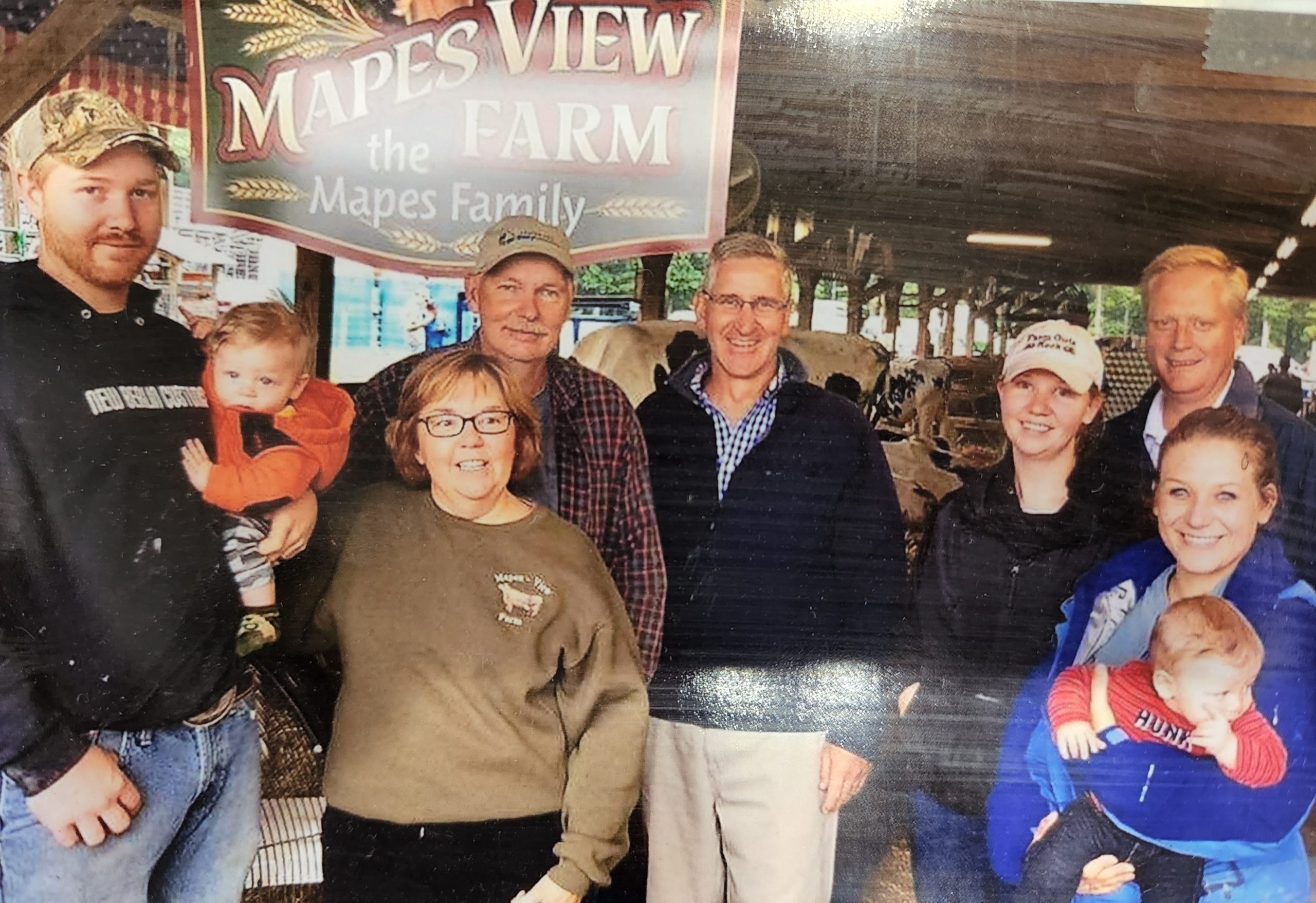 The Mapes family is in front of the Mapes View Farm sign.