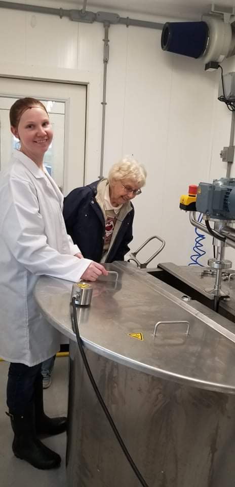 A young dairy farmer and her grandmother next to the processing machine.