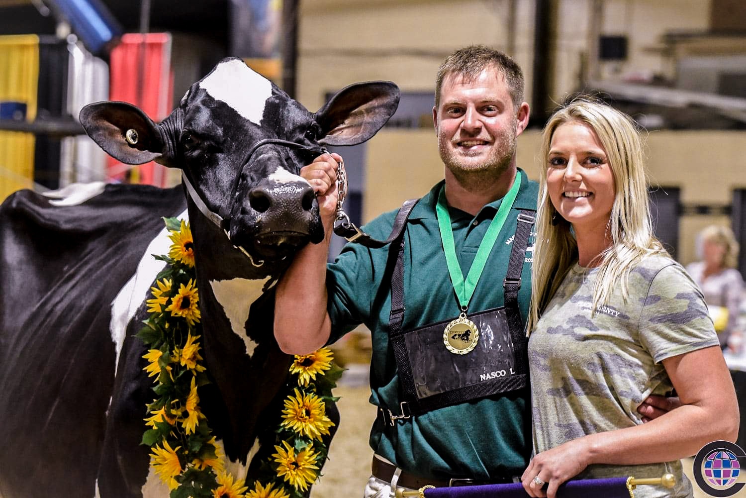 A couple of dairy farmers standing next to a dairy cow at the Maryland State Fair.