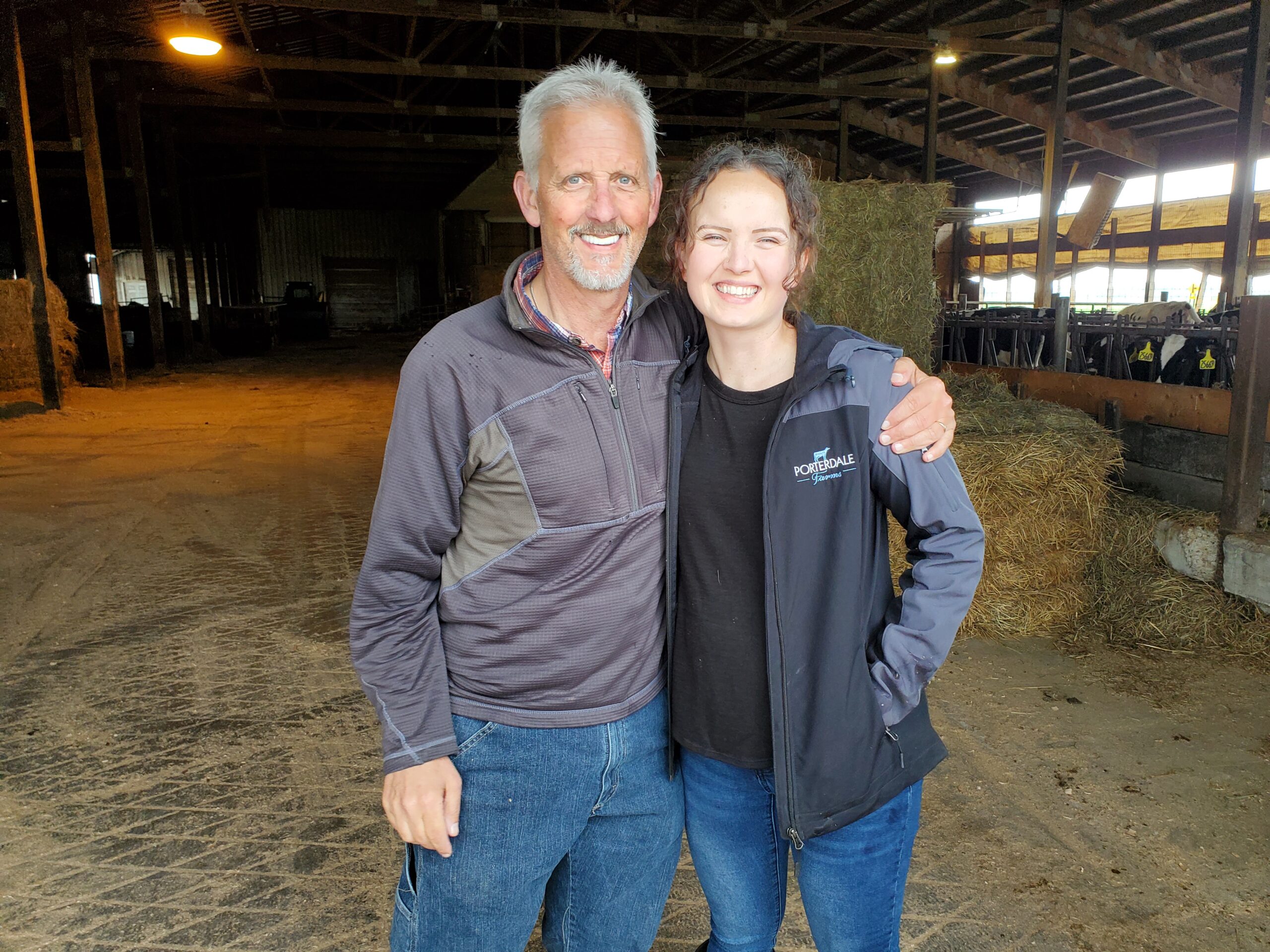 A farmer for Porterdale farms hugging his daughter, while both of them smile towards a camera.