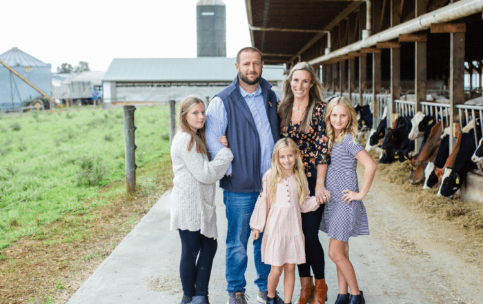 The Crothers dairy family posing in front of a row of cows at Long Green Farm.