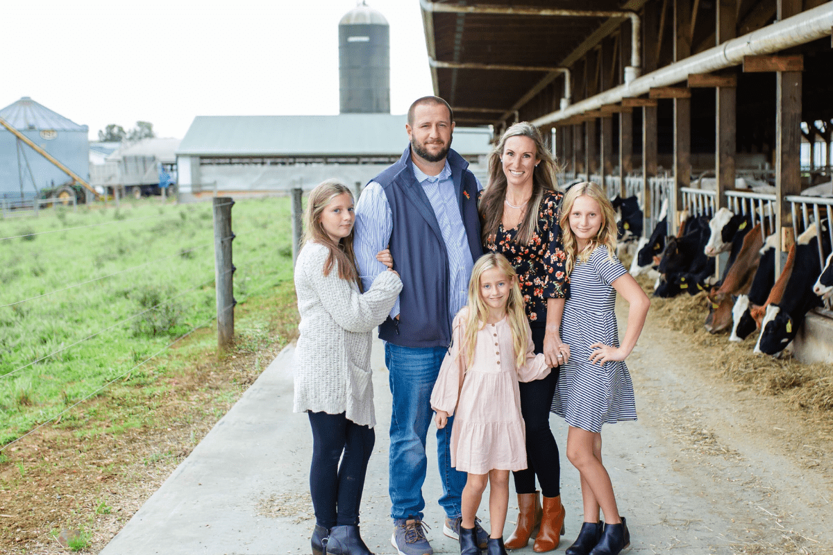 The Crothers dairy family posing in front of a row of cows at Long Green Farm.