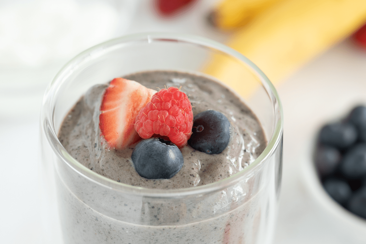 A smoothie served in a glass and topped with fruit.