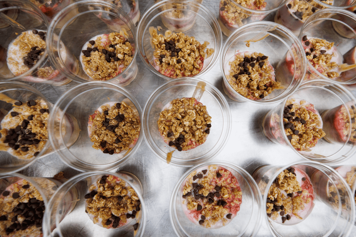 An overhead picture of multiple yogurt and granola parfaits served in cups.