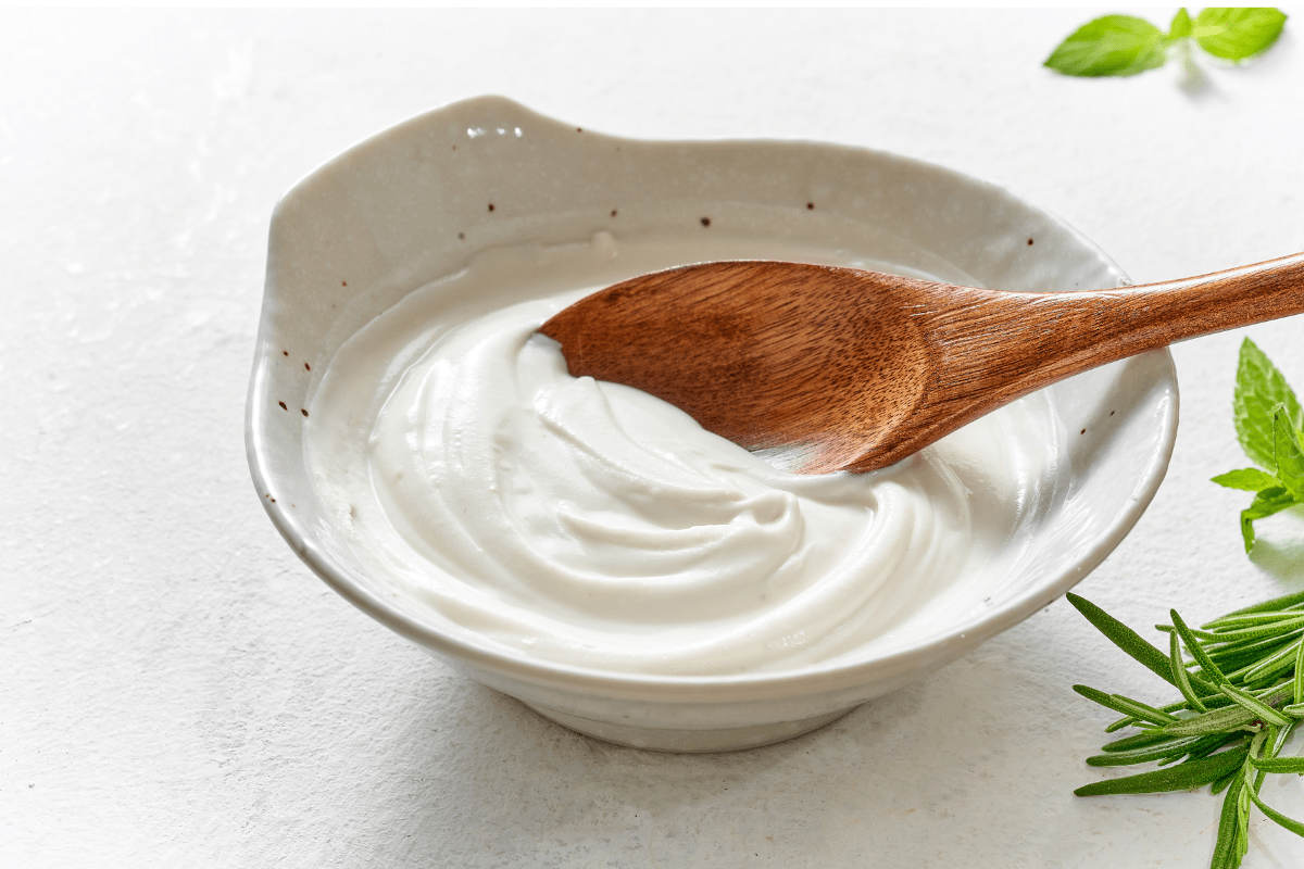 A bowl of Greek yogurt with a wooden spoon in it.